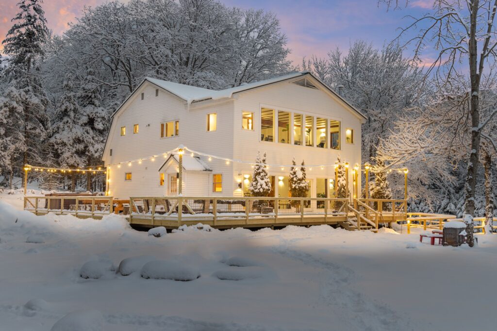 A beautiful white house surrounded by the trees on a snowy winter day
